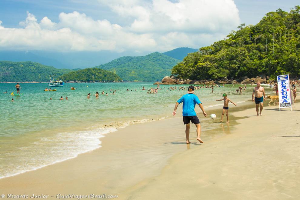 Imagem de pai e filho jogando bola na beira da Praia da Almada em Ubatuba.